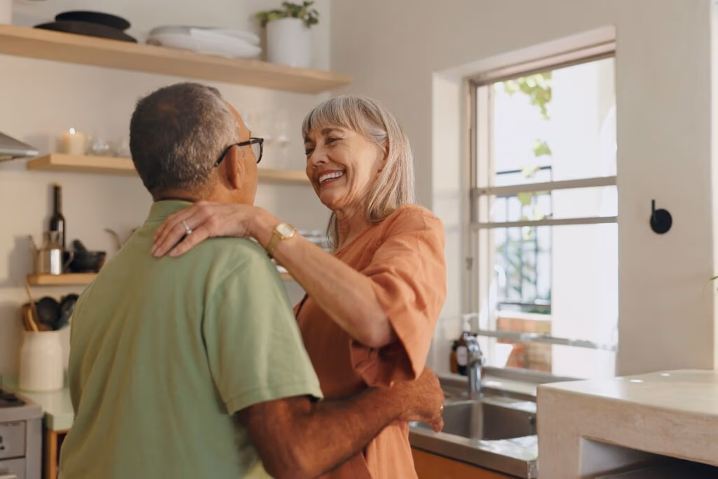 An older couple dancing together at home.