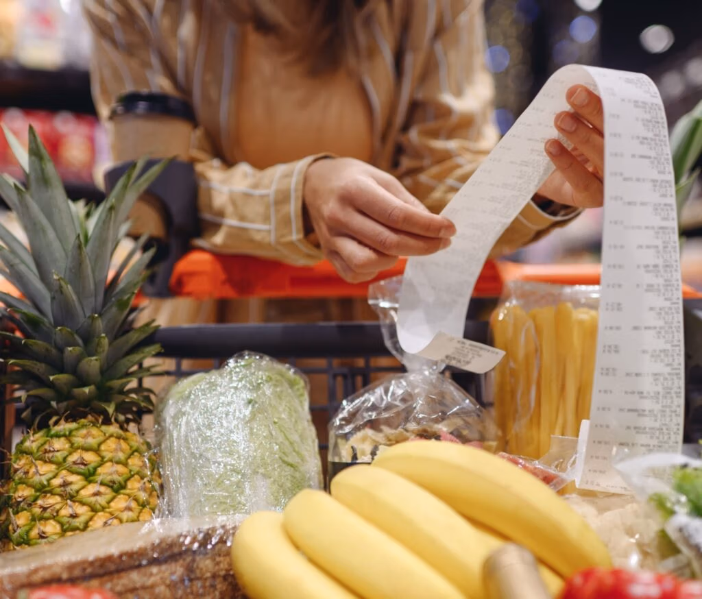 A woman looking at a receipt in a supermarket.