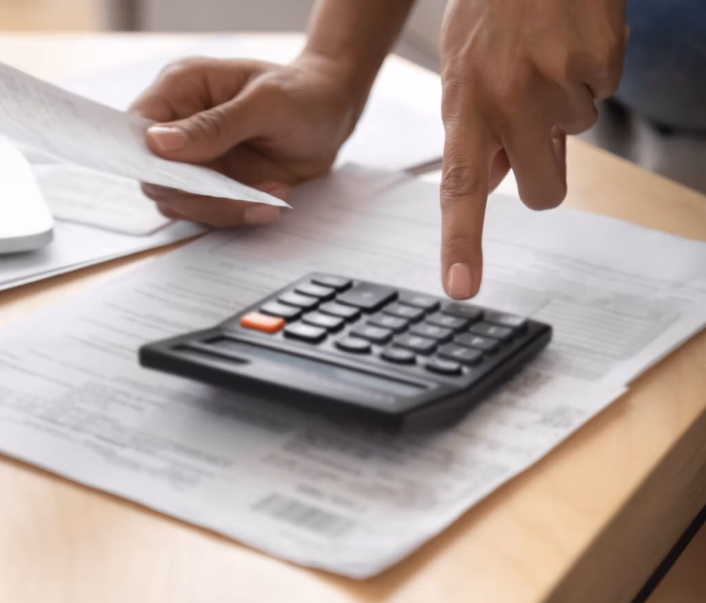 A person going through paperwork with a calculator.