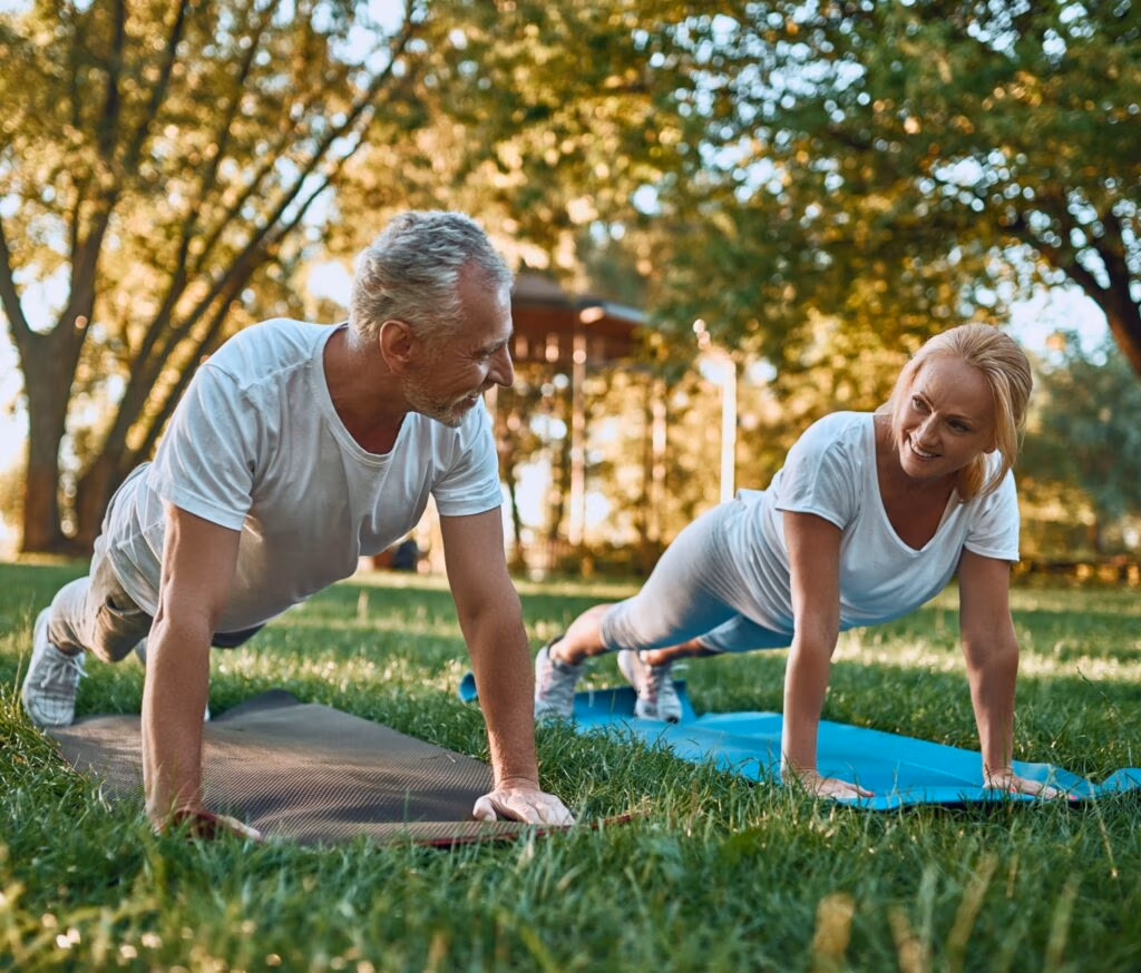 A couple doing yoga in a park.