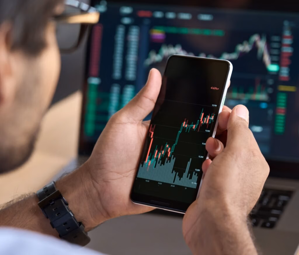 A man looking at a graph showing stock market performance on his phone.