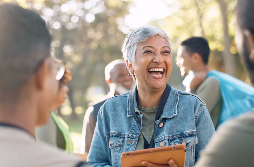 A woman with a clipboard volunteering at an event in a park.
